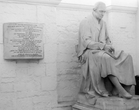 A photograph of a life-size statue of James Watt, an older white man dressed in flowing robes.